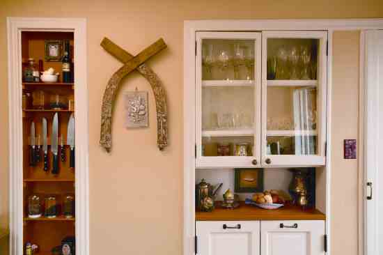 The tea and knife niche in the wall beside the stove, original to the kitchen, is painted in the dining nook’s pumpkin- spice tone.